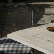 Ashtray on patio table next to metal chair with fabric seat cushion