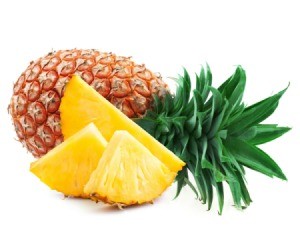 Whole fresh pineapple laying on it's size with fresh pineapple slices