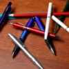 Pile of assorted pens on a wooden table