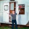 Woman standing in front of a travel trailer that has a "Home for Rent" sign in the window