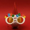 Piggy Bank wearing Happy Birthday glasses and a party hat against a red background