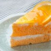 Slice of orange cake on a white plate (topped with an orange slice)