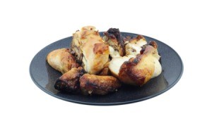 Several pieces of grilled chicken on a black plate against a white background