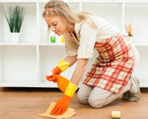 Woman cleaning floor with orange spray bottle and rag