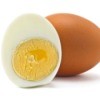 One brown egg and one half of a peeled hard boiled egg against a white background
