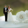 Bride and Groom figurines on the top of a wedding cake with a flower