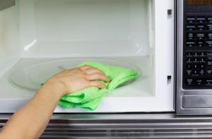 Hand cleaning inside of a microwave oven with a rag