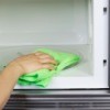 Hand cleaning inside of a microwave oven with a rag