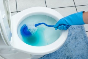 A toilet being cleaned with blue water.