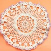 White doily with purple edges against an orange background.  Doily does not appear to be starched