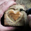 Close up of rotary tool being used to carve a heart in a wood block