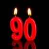 Lit candles in the shape of "90" against a white background