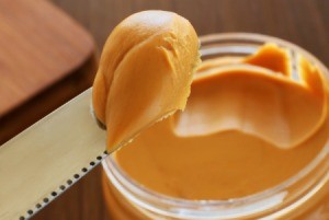 Close up of knife holder peanut butter over the top of a peanut butter jar