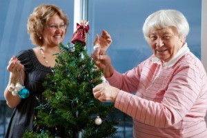 Volunteer helping senior adult woman decorate a Christmas Tree
