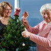 Volunteer helping senior adult woman decorate a Christmas Tree