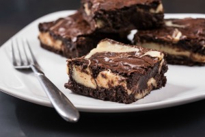 Brownie cheese cake squares on a white plate