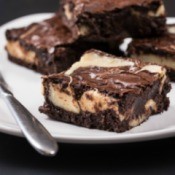 Brownie cheese cake squares on a white plate