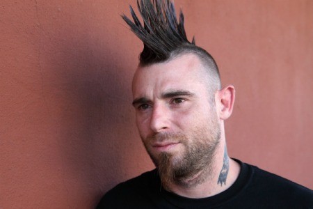 Man with spiked mohawk against brick colored background