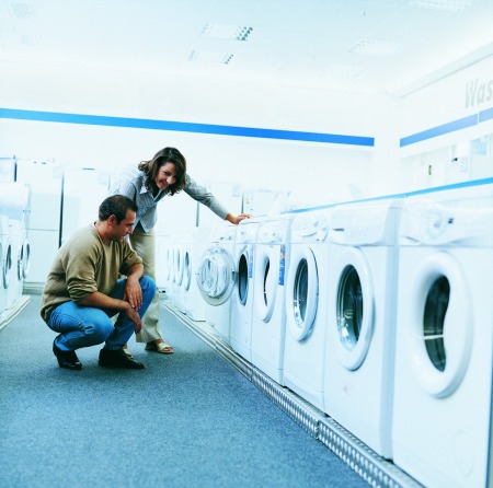 Couple shopping for a front loading clothes washer in a department store.