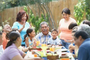 Several generations of a family laughing around a decorated table outdoors.