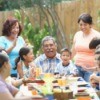Several generations of a family laughing around a decorated table outdoors.