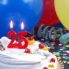 Candles in the shape of the number 25 on a cake in front of balloons, confetti and streamers