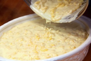 Macaroni and cheese being poured from a saucepan to a serving dish