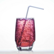Glass of Grape soda with ice and a straw against a white background