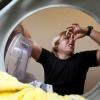 View from inside of a front load washing machine of a man holding his nose.