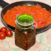 Pan of spaghetti sauce with jar of chili sauce and tomatoes in front