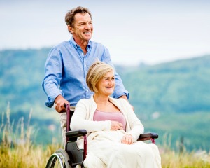 Man pushing woman in a wheelchair against a beautiful view.