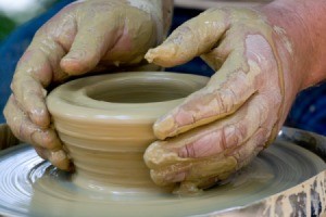 Hands forming a bowl on a pottery wheel
