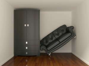 Small room containing a cabinet that is too large for the space and a tilted couch that won't fit