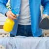 Man holding spray bottle in one hand and an iron in the other