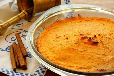 Carrot Souffle in glass dish with sticks of cinnamon beside it.