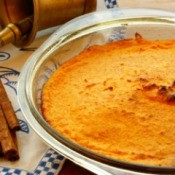Carrot Souffle in glass dish with sticks of cinnamon beside it.