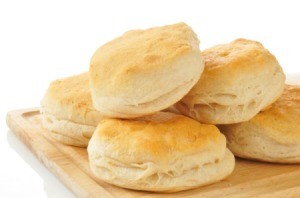 Several biscuits piled on a cutting board against a white background