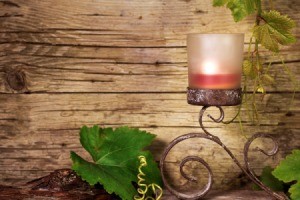 Candle on wrought iron scroll design holder with imitation grape vines