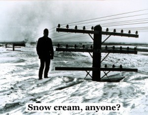 black and white photo of man standing on snow bank up to the lower cross member of a power pole