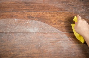 Hand wiping white residue off wooden floor