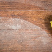 Hand wiping white residue off wooden floor