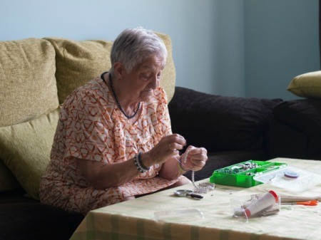 Elderly woman stringing beads