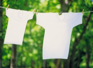Two white t-shirts hanging on a clothes line
