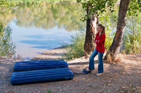 Woman pumping up air mattress in the woods