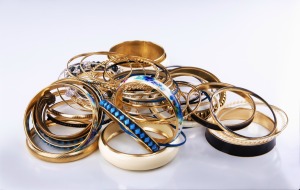 Unorganized pile of gold bracelets on a white surface