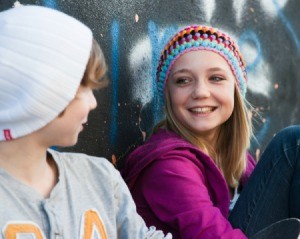 Young teen-age girl and boy sitting against a wall