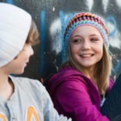 Young teen-age girl and boy sitting against a wall