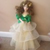 doll wearing dress with green top and three layered skirt