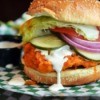 Close up of a chicken sandwich with dressing pouring out from between the buns
