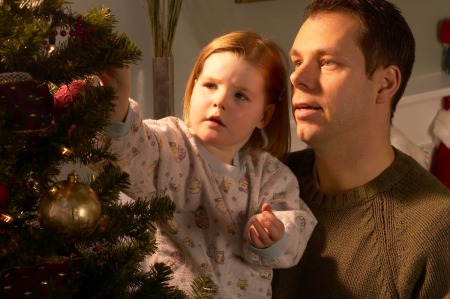 Father and young girl decorating a Christmas tree
